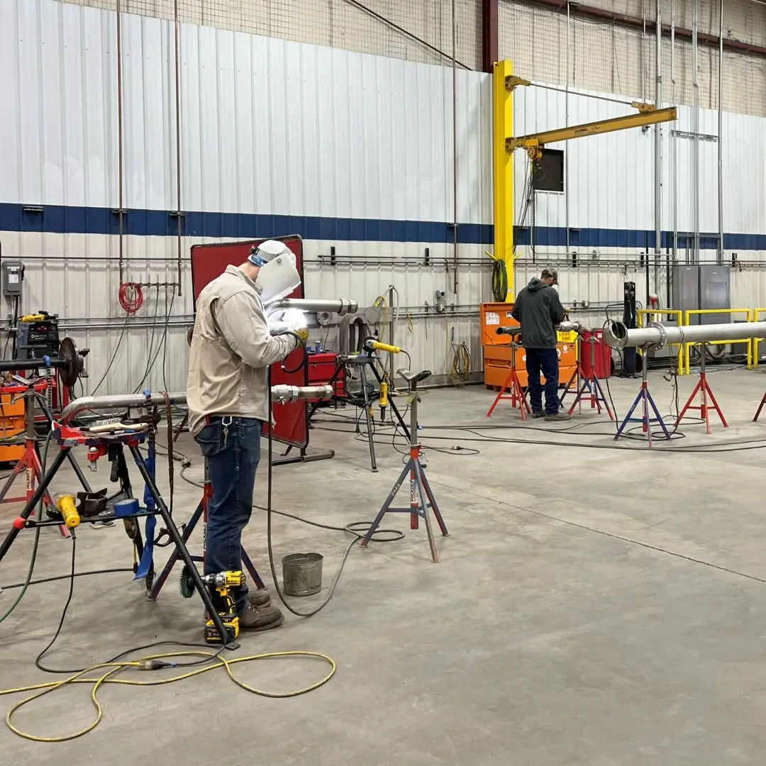 Welders working on pipe spools in a fabrication workshop